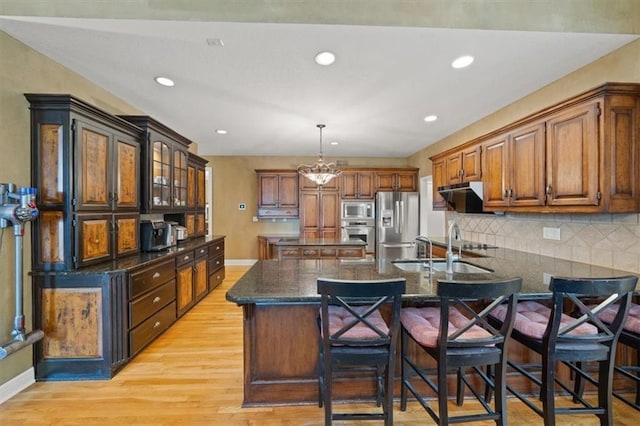 5817 W 147th Pl, Overland Park, KS 66223 - kitchen featuring appliances with stainless steel finishes, a peninsula, backsplash, a breakfast bar area, and range hood