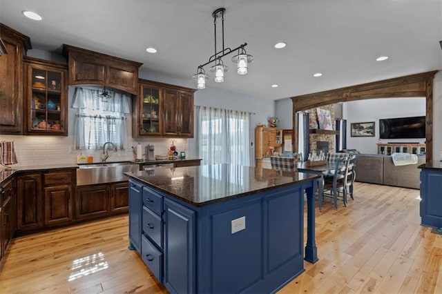 30307 Woodland Dr, Pleasant Hill, MO 64080 - kitchen featuring a sink, a kitchen island, open floor plan, light wood-style floors, and decorative backsplash
