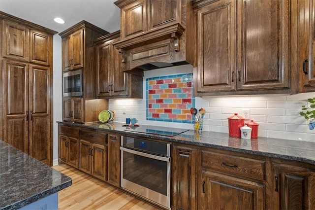 30307 Woodland Dr, Pleasant Hill, MO 64080 - kitchen featuring appliances with stainless steel finishes, light wood-type flooring, dark stone counters, backsplash, and recessed lighting