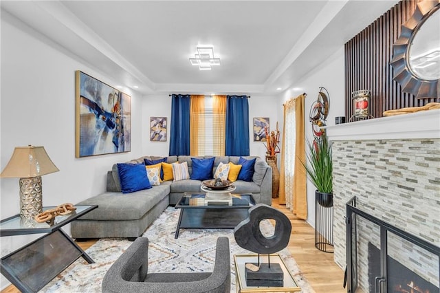 living area featuring a fireplace, a raised ceiling, and wood finished floors