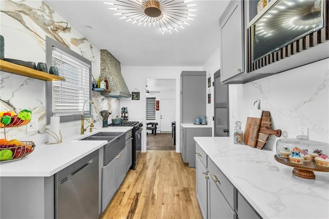 kitchen with gray cabinetry, open shelves, black gas range, stainless steel dishwasher, and premium range hood