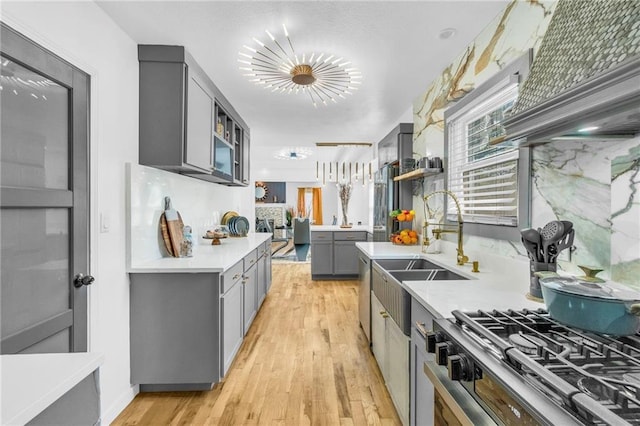 kitchen with gray cabinetry, a sink, light countertops, and light wood-type flooring