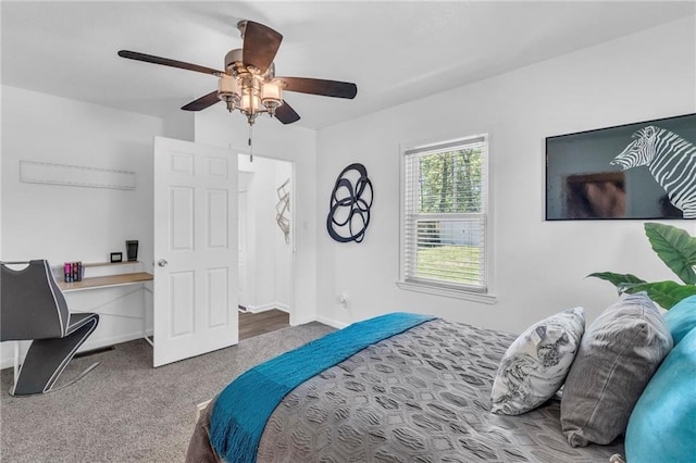 carpeted bedroom with ceiling fan, a desk, and baseboards