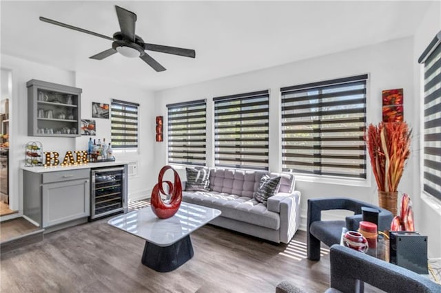 living room with wine cooler, a bar, wood finished floors, and ceiling fan