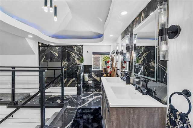 full bathroom with marble tiled flooring, a raised ceiling, vanity, and recessed lighting