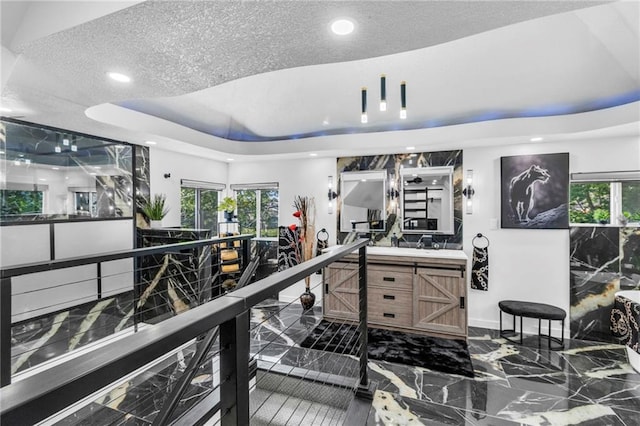 miscellaneous room with marble tiled flooring, recessed lighting, a tray ceiling, and baseboards