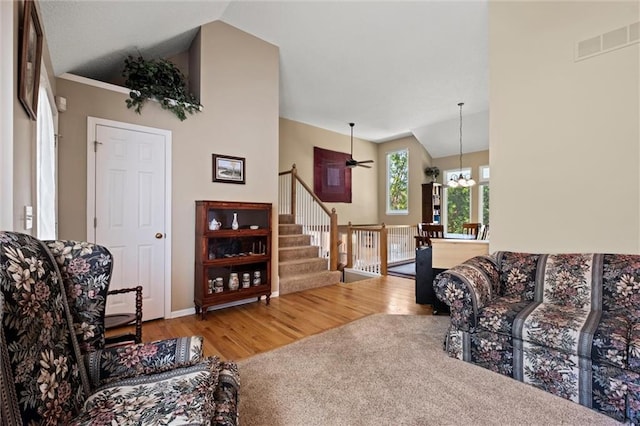 12434 England St, Overland Park, KS 66213 - living area with lofted ceiling, wood finished floors, stairway, a chandelier, and a ceiling fan