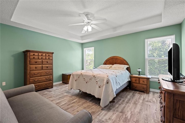 12434 England St, Overland Park, KS 66213 - bedroom featuring a raised ceiling, a textured ceiling, light wood-style floors, baseboards, and a ceiling fan