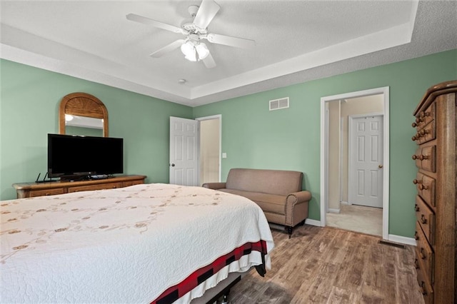 12434 England St, Overland Park, KS 66213 - bedroom with a raised ceiling, wood finished floors, baseboards, and ceiling fan