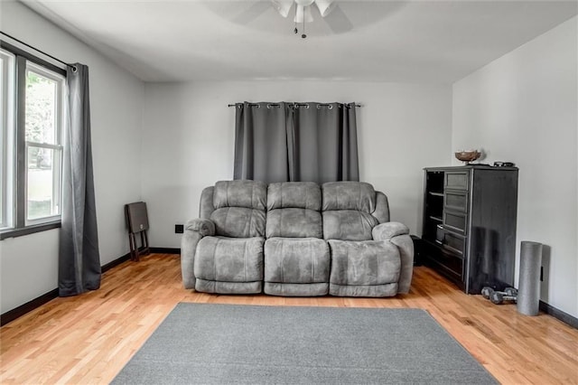 living room with ceiling fan, light wood-style floors, and baseboards