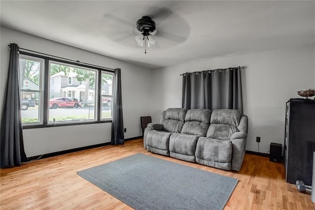 living room with a ceiling fan, light wood-type flooring, and baseboards