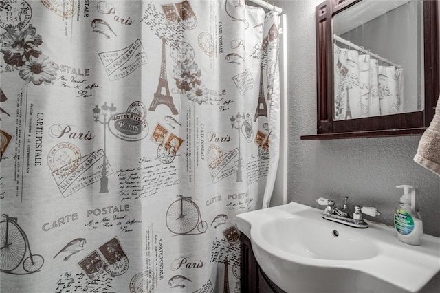 full bathroom with a textured wall and vanity