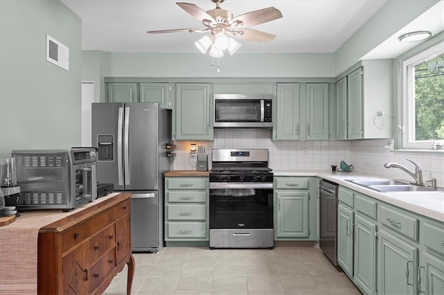 613 NE 90th Ter, Kansas City, MO 64155 - kitchen with appliances with stainless steel finishes, a ceiling fan, light countertops, decorative backsplash, and green cabinets