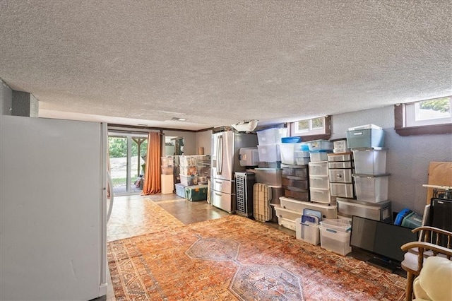 613 NE 90th Ter, Kansas City, MO 64155 - basement with a textured ceiling, freestanding refrigerator, and stainless steel fridge with ice dispenser