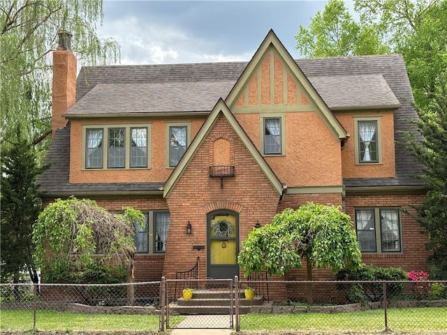 2702 Faraon St, Saint Joseph, MO 64501 - tudor-style house with a chimney, roof with shingles, a fenced front yard, and brick siding