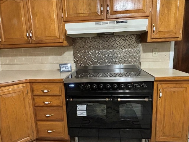 2702 Faraon St, Saint Joseph, MO 64501 - kitchen featuring under cabinet range hood, range with two ovens, light countertops, and backsplash