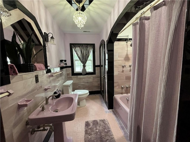 2702 Faraon St, Saint Joseph, MO 64501 - bathroom featuring tile walls, toilet, tile patterned floors, shower / bathtub combination with curtain, and a wainscoted wall