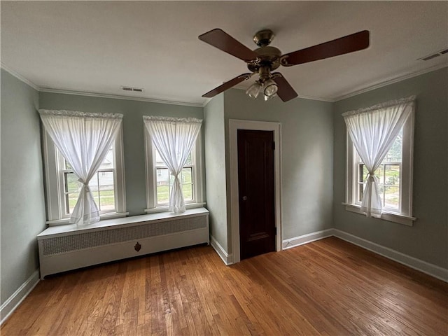 2702 Faraon St, Saint Joseph, MO 64501 - empty room featuring crown molding, healthy amount of natural light, wood finished floors, and radiator