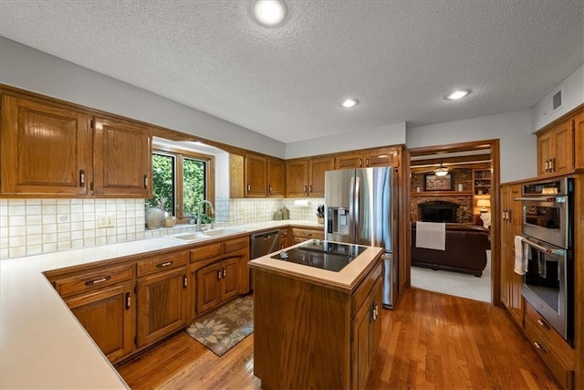 12224 Connell Dr, Overland Park, KS 66213 - kitchen featuring stainless steel appliances, light countertops, brown cabinets, a kitchen island, and a textured ceiling