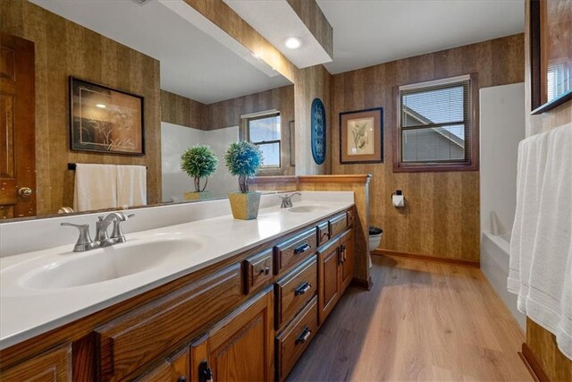 12224 Connell Dr, Overland Park, KS 66213 - full bath featuring wood finished floors, double vanity, wallpapered walls, and shower / tub combination