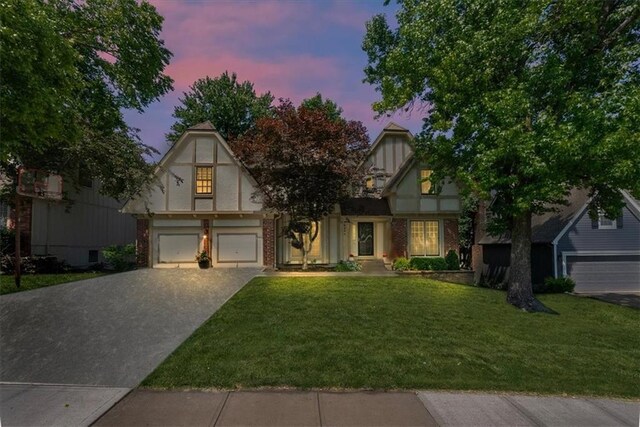 12224 Connell Dr, Overland Park, KS 66213 - english style home featuring a garage, driveway, a front lawn, and brick siding