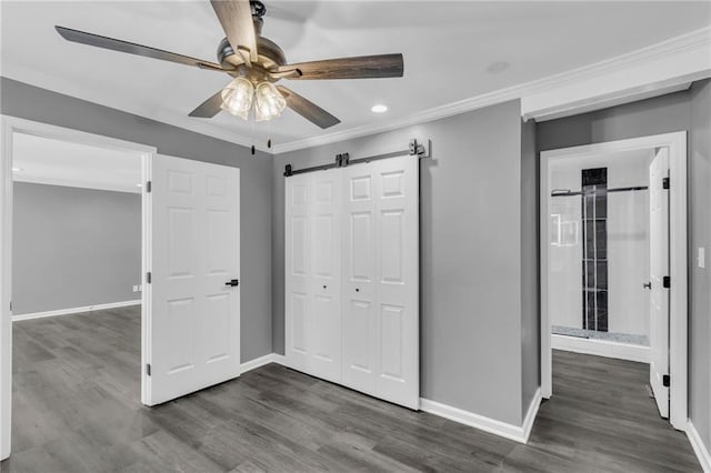 6531 W 49th St, Mission, KS 66202 - unfurnished bedroom with a barn door, dark wood-style floors, baseboards, ornamental molding, and a closet
