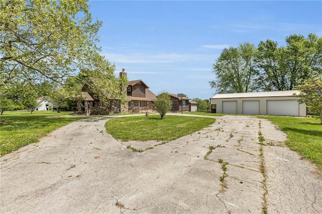 view of front of property featuring a detached garage, a front lawn, an outbuilding, and a chimney