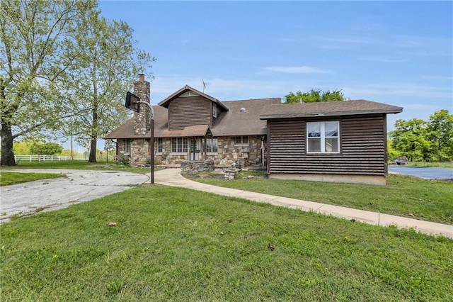 view of front of home featuring a front yard, a chimney, and stone siding