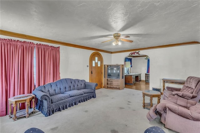 living area featuring arched walkways, carpet flooring, ceiling fan, and crown molding