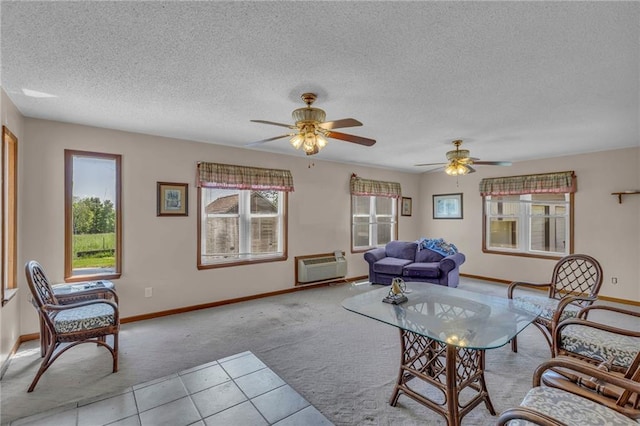 carpeted living area with a textured ceiling, baseboards, a wall mounted AC, and ceiling fan