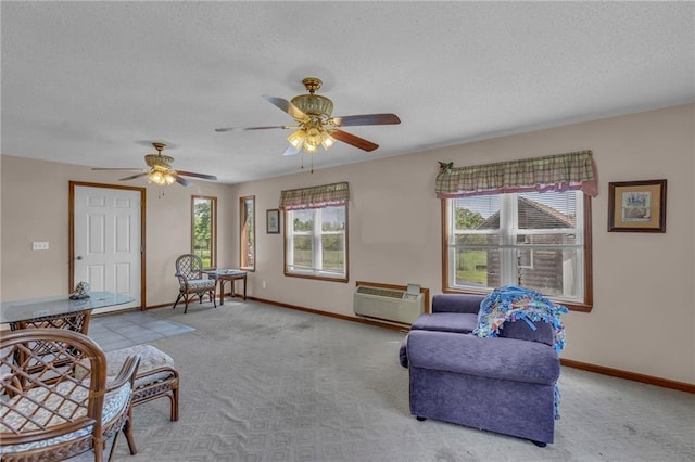 living room with a wall unit AC, carpet, a textured ceiling, a ceiling fan, and baseboards