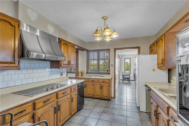 kitchen with black electric cooktop, a chandelier, brown cabinets, ventilation hood, and a textured ceiling