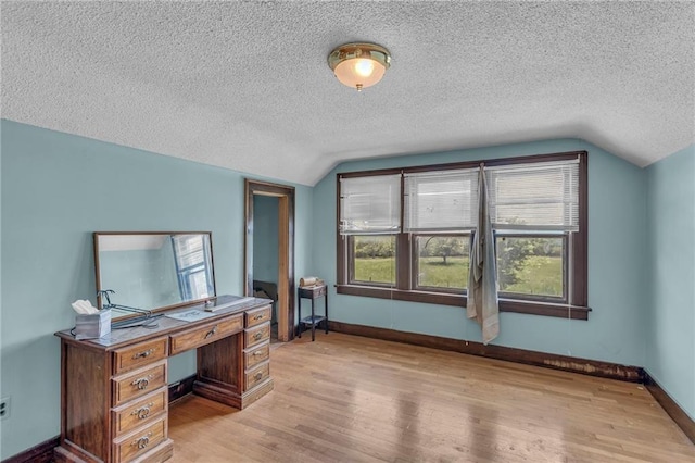 home office featuring vaulted ceiling, light wood-style floors, a textured ceiling, and baseboards