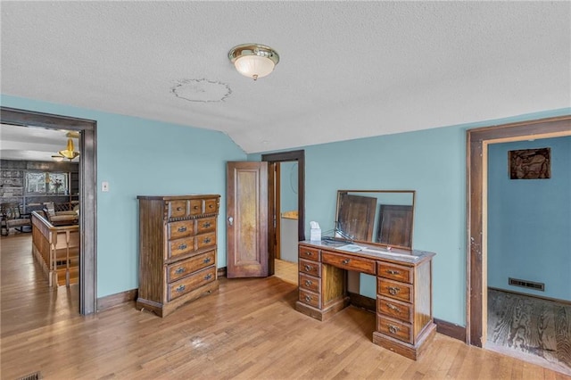 bedroom featuring a textured ceiling, wood finished floors, baseboards, and vaulted ceiling