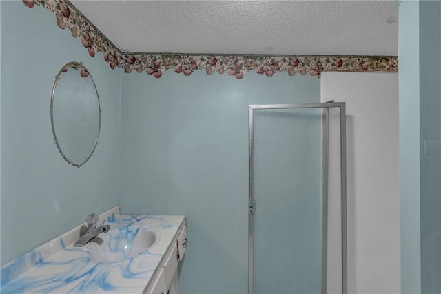 bathroom with a textured ceiling, a stall shower, and vanity