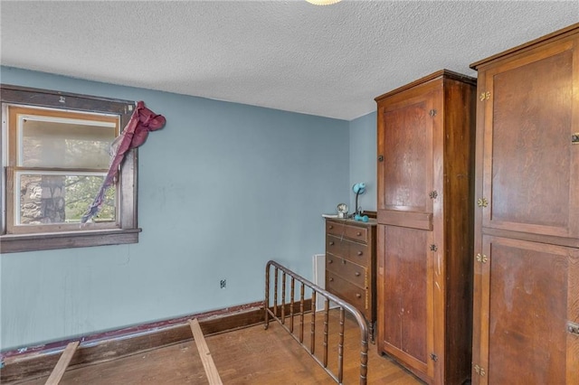 staircase with a textured ceiling, wood finished floors, and baseboards