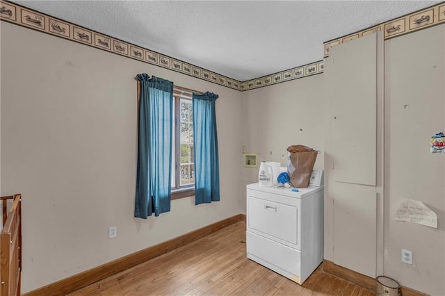 laundry room with washer / dryer, light wood-type flooring, a textured ceiling, and baseboards