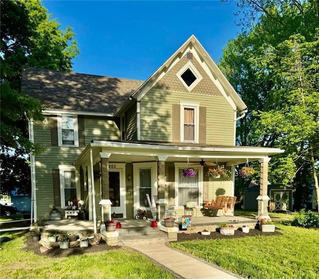 203 S Hughes St, Hamilton, MO 64644 - victorian house with covered porch, a front yard, and a storage unit