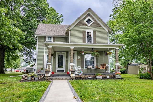 203 S Hughes St, Hamilton, MO 64644 - victorian-style house with a storage shed, a porch, a front lawn, ceiling fan, and a shingled roof