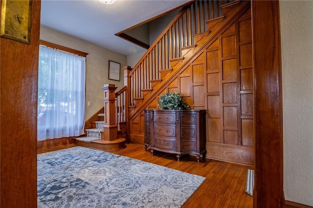 203 S Hughes St, Hamilton, MO 64644 - foyer featuring wood finished floors, stairway, and a textured wall
