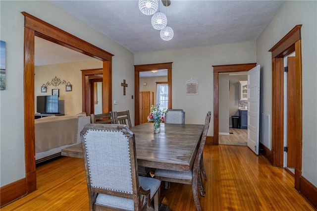 203 S Hughes St, Hamilton, MO 64644 - dining room with a chandelier, light wood-style flooring, and a textured ceiling