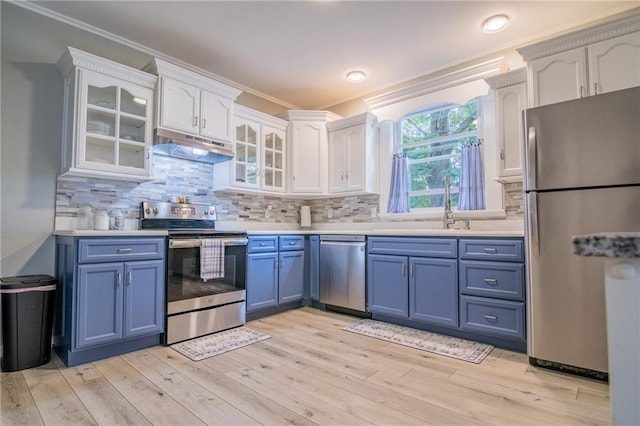 203 S Hughes St, Hamilton, MO 64644 - kitchen featuring appliances with stainless steel finishes, under cabinet range hood, blue cabinets, crown molding, and white cabinetry