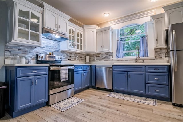 203 S Hughes St, Hamilton, MO 64644 - kitchen featuring stainless steel appliances, blue cabinetry, under cabinet range hood, ornamental molding, and white cabinetry