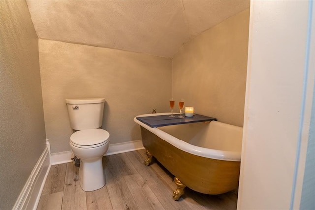203 S Hughes St, Hamilton, MO 64644 - bathroom with wood-type flooring, a freestanding tub, lofted ceiling, and a textured wall