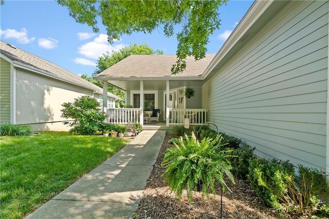 view of exterior entry with a porch and a yard