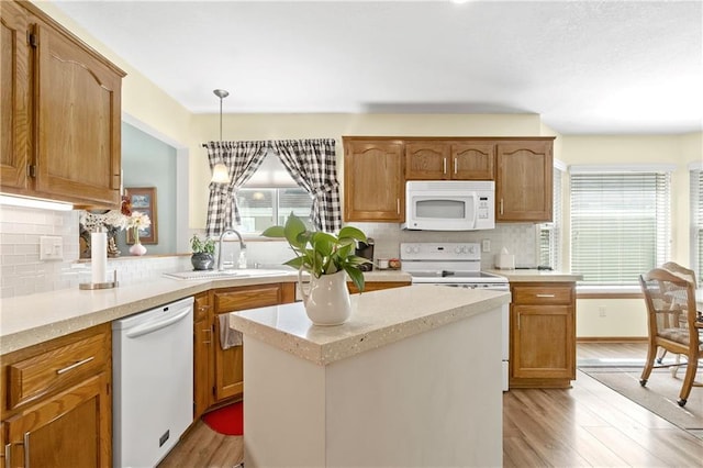 kitchen featuring white appliances, a sink, backsplash, and light wood finished floors