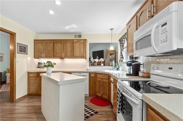 kitchen with white appliances, backsplash, light countertops, wood finished floors, and recessed lighting