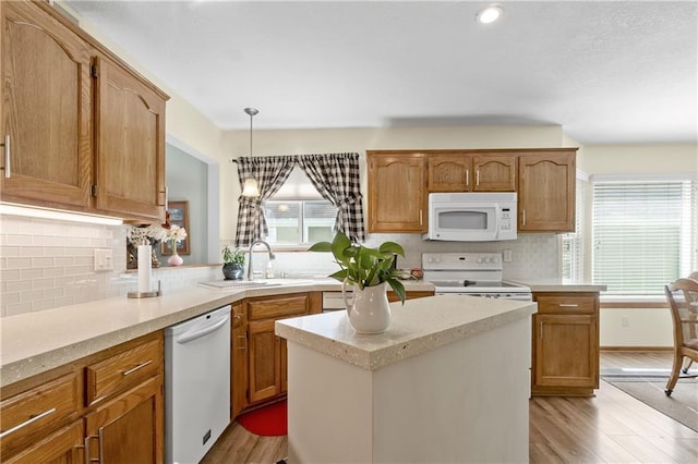 kitchen with white appliances, light wood-style flooring, tasteful backsplash, and a sink