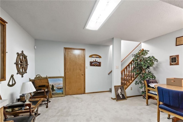 living area with light carpet, stairs, a textured ceiling, and baseboards