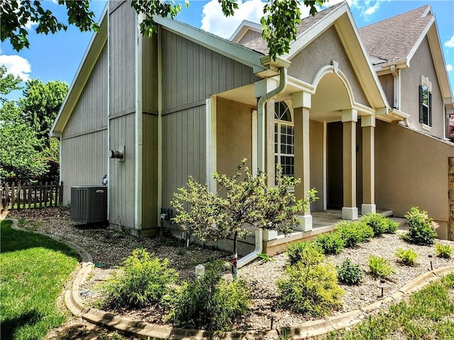view of property exterior with central AC unit, fence, roof with shingles, and stucco siding